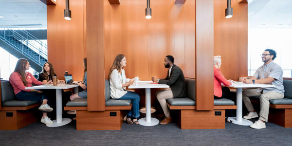 a group of people sitting at tables in a room with wood walls
