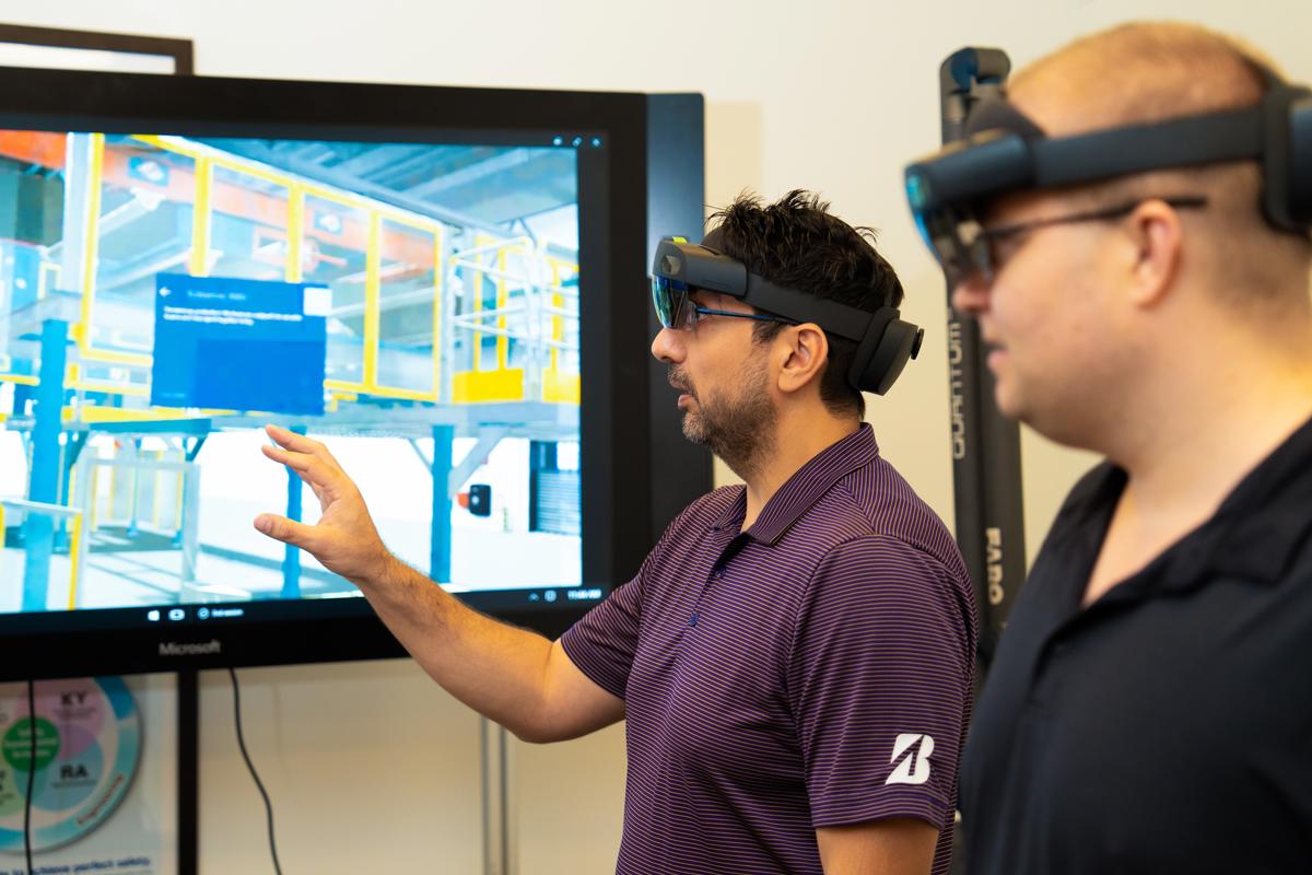 a man wearing virtual reality goggles pointing at a screen